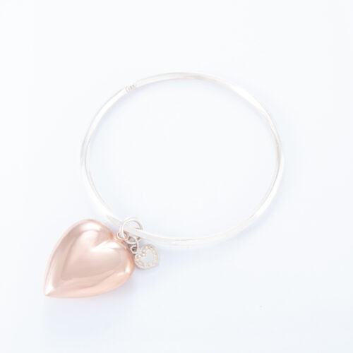 Our 2 Tone Large Puffed Heart Bangle. Shown here, handcrafted in a bevel-edged 925 sterling silver band. Also with a beautiful large puffed rose gold heart. As well as, with a small sterling heart. It's a truly unique and stunning piece. In short, the ultimate gift idea, with twice the love. Or as a self-indulgent purchase to add to your own personal jewelry collection.