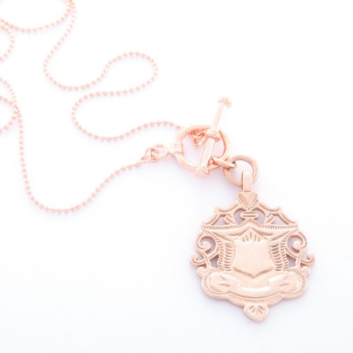 Our 18 Inch Rose Gold Shield Ball Chain Necklace. Shown here, beautifully handcrafted in a pink gold finish. And also, engraved and plated over 925 sterling silver. In short, this timeless piece is simply stunning. The ultimate self-indulgent addition to your jewelry collection. Or as a unique gift purchase for someone extra special.