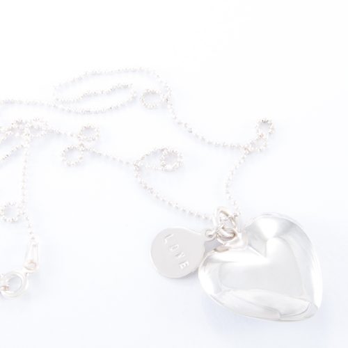 Our Fine Sterling Silver Small Puffed Heart Ball Chain Necklace. Shown here beautifully handcrafted in 925 sterling. Also paired with a small sterling love disc. In short, this stunning piece is elegant, timeless, and full of style. The perfect gift idea for someone special. Or as a self-indulgent addition to your own jewelry collection.