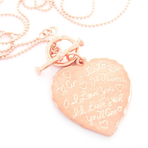 Our Rose Gold Tiamo Fob Necklace. Shown here, with a beautiful ball chain and engraved heart charm. Also handcrafted in pink gold plated over 925 sterling. In short, this piece is absolutely stunning. The ultimate self-indulgent addition to any personal jewelry collection. Or as a gift idea for somebody special.
